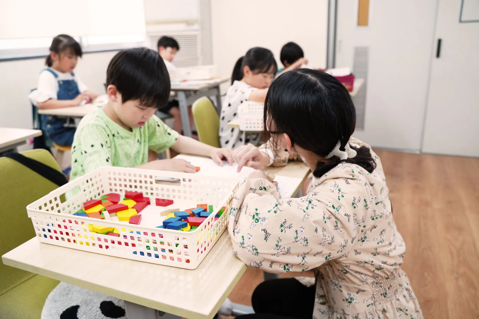 教室で図形ブロックとプリントを使い、謎チャレに取り組む子どもたち