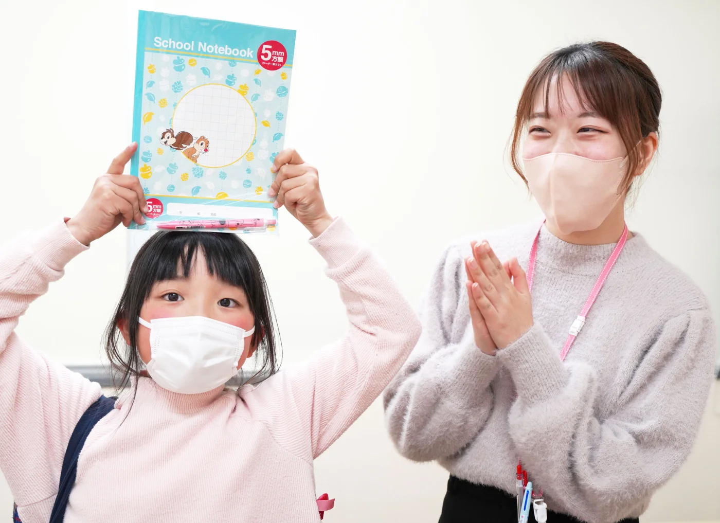 ノートを掲げる子どもを、拍手してほめる先生