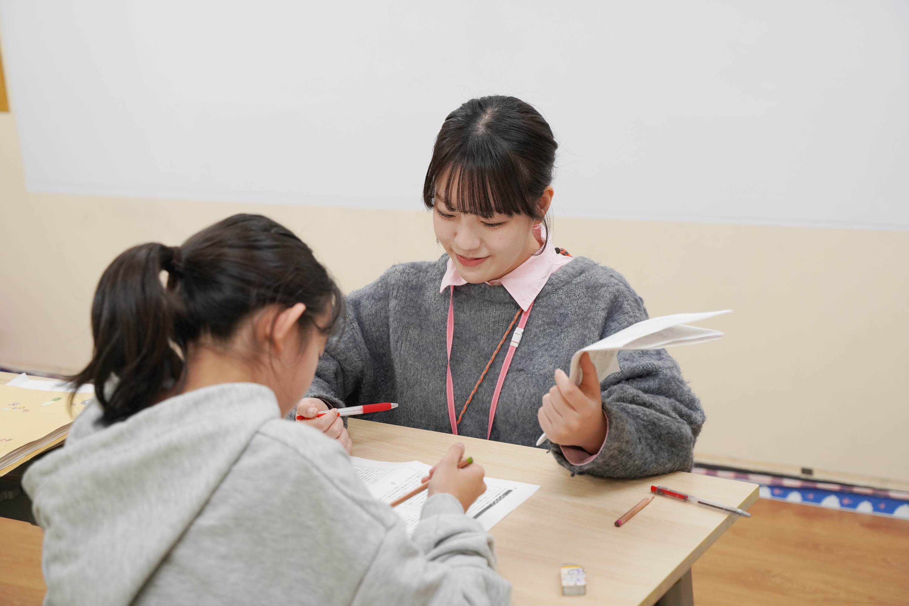 教材を広げ、先生と一緒に学ぶ生徒